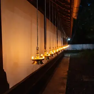 Row of hanging brass deepam lamps along the temple corridor